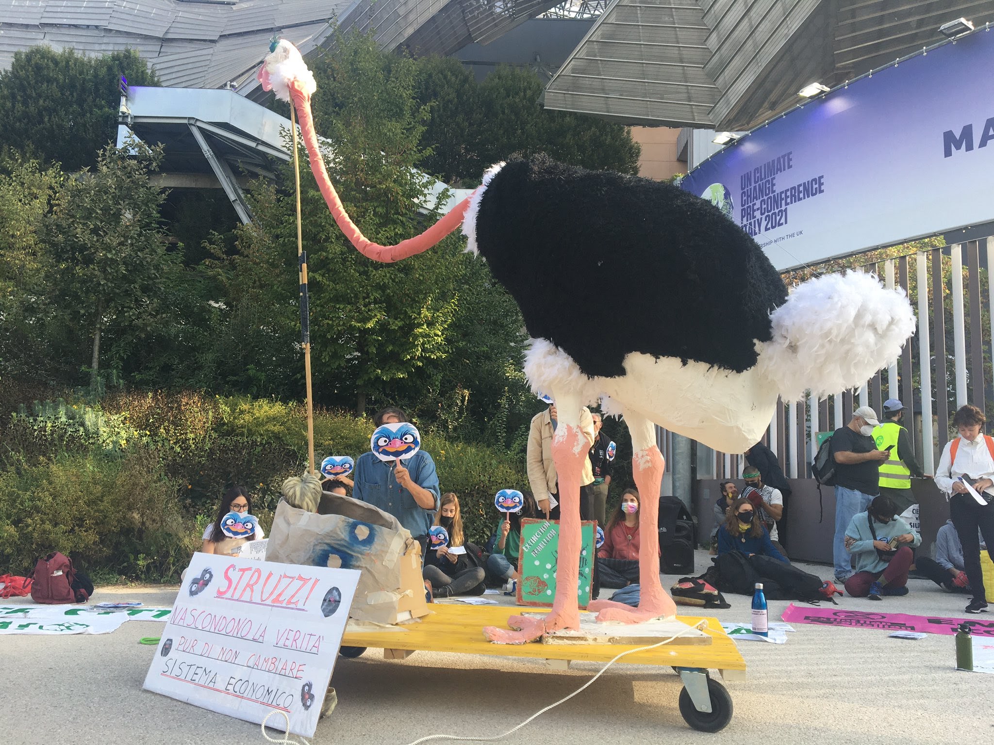 A giant model of an ostrich stands with kneeling rebels outside the Milan Convention Centre